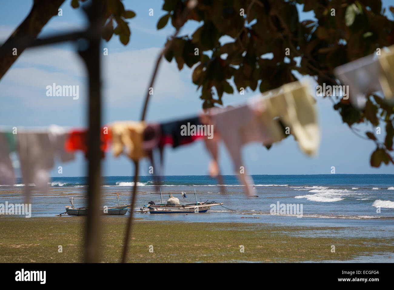 Fischerboote und sonnentrocknende Kleidung am Strand von Tanjung Setia in Krui, an der Westküste von Lampung, Indonesien. Stockfoto
