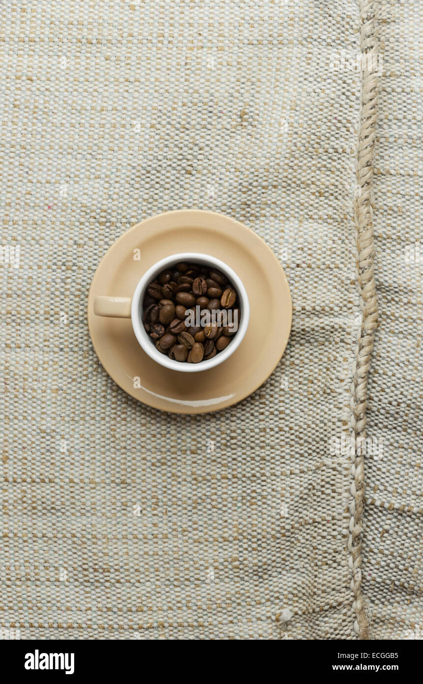 Kaffeebohnen in eine Tasse über rustikale Sackleinwand, über Ansicht Stockfoto