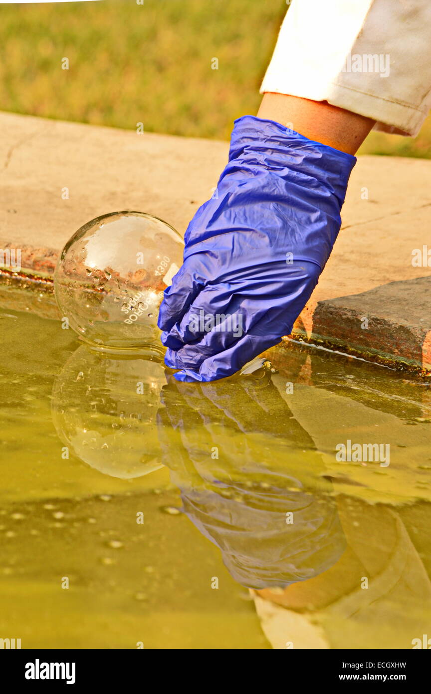 Umwelt Ökologie Verschmutzung Wasser Probenahme Hand Handschuh Wissenschaftler Wissenschaft Forschung "Verschmutzung" Kolben Analyse Wasserteich Stockfoto