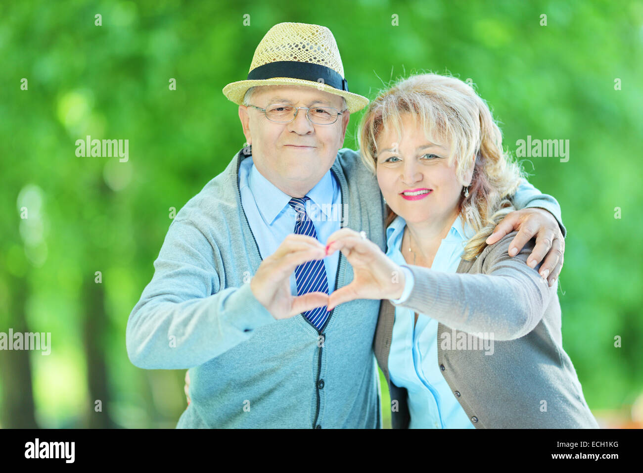Älteres Paar, so dass eine Herzform mit ihren Händen in einem park Stockfoto
