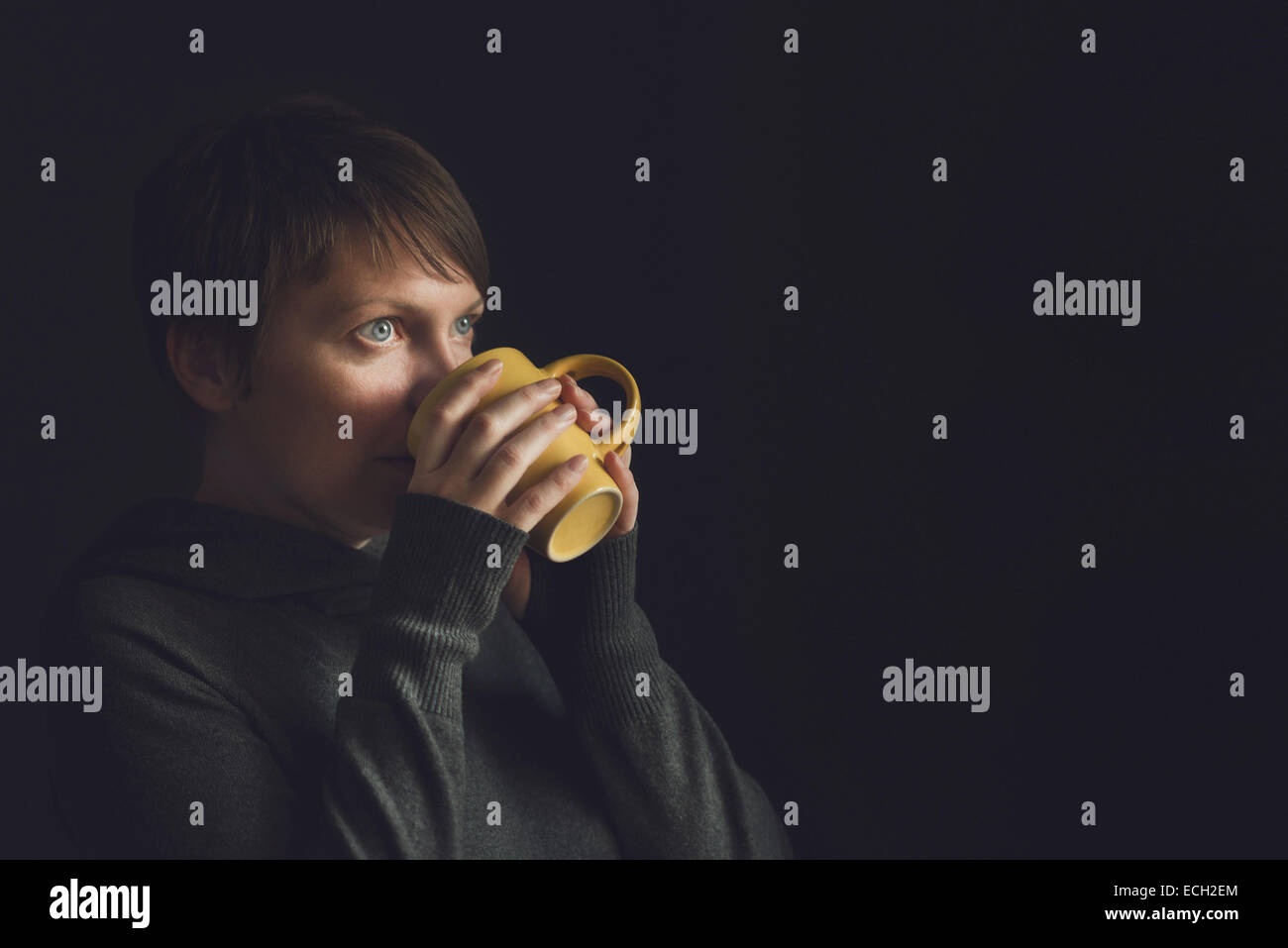 Schöne kaukasischen erwachsenen Frau im dunklen Raum Tasse Tee trinken. Selektiven Fokus mit geringen Schärfentiefe. Stockfoto