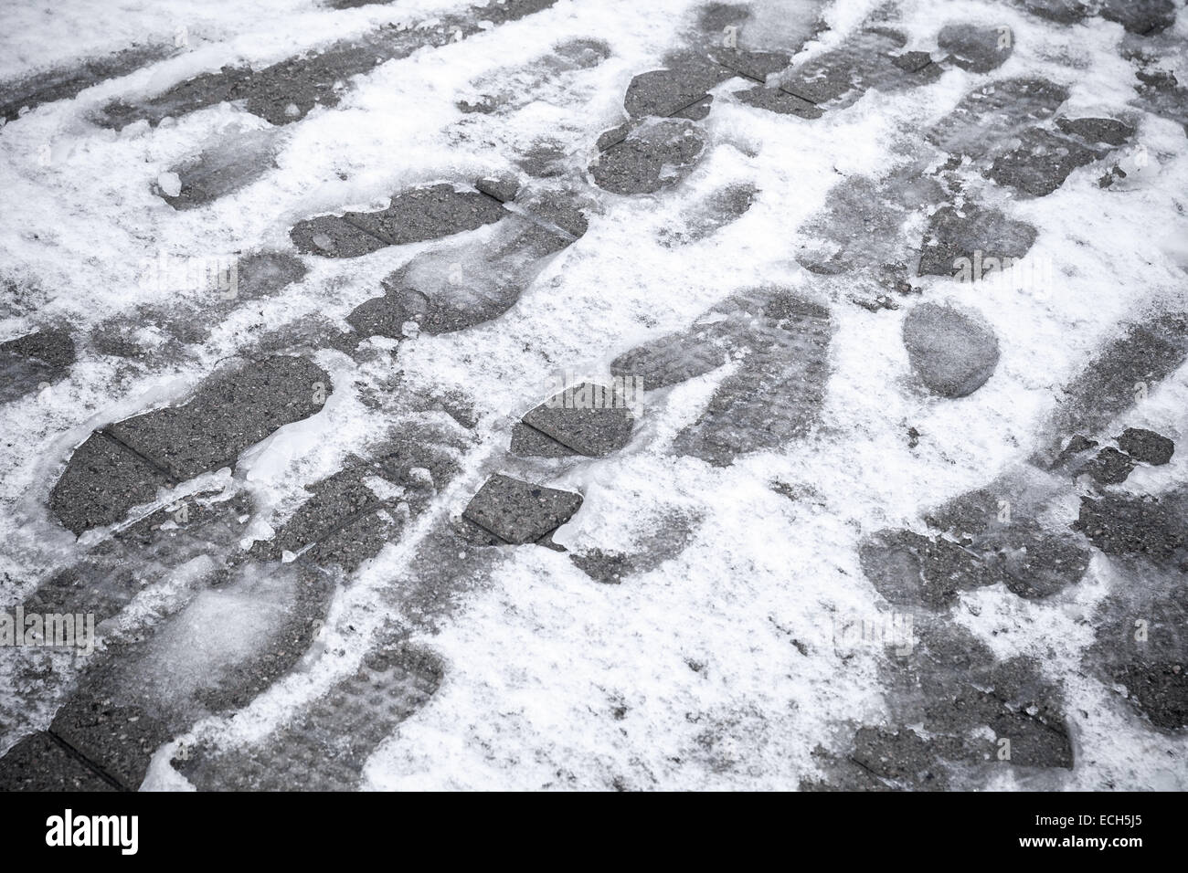 Fußspuren im nassen Neuschnee auf der Straße Stockfoto