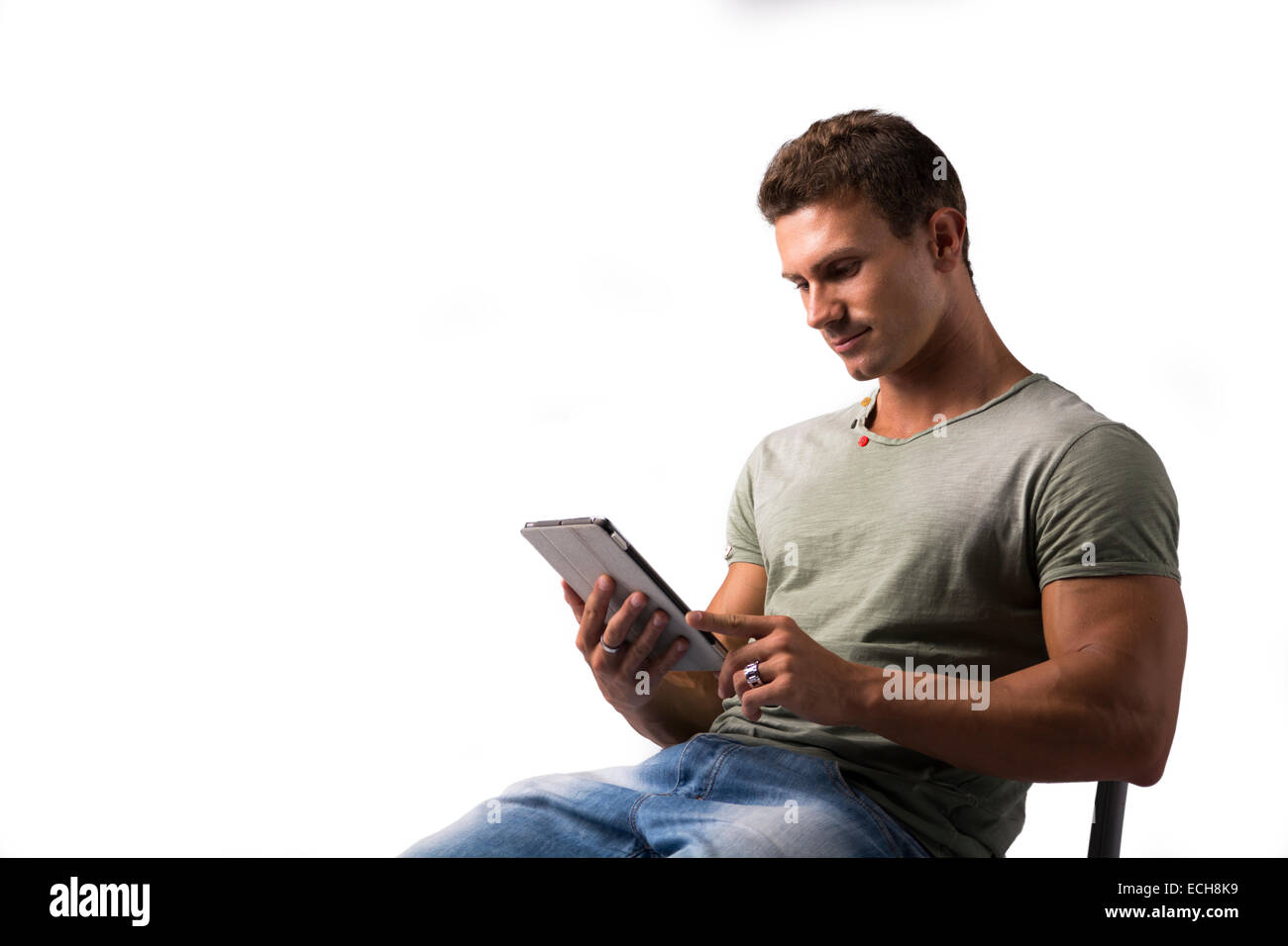 Attraktive junge Mann hält Ebook-Reader und lächelnd, sitzt isolierten auf weißen Hintergrund Stockfoto