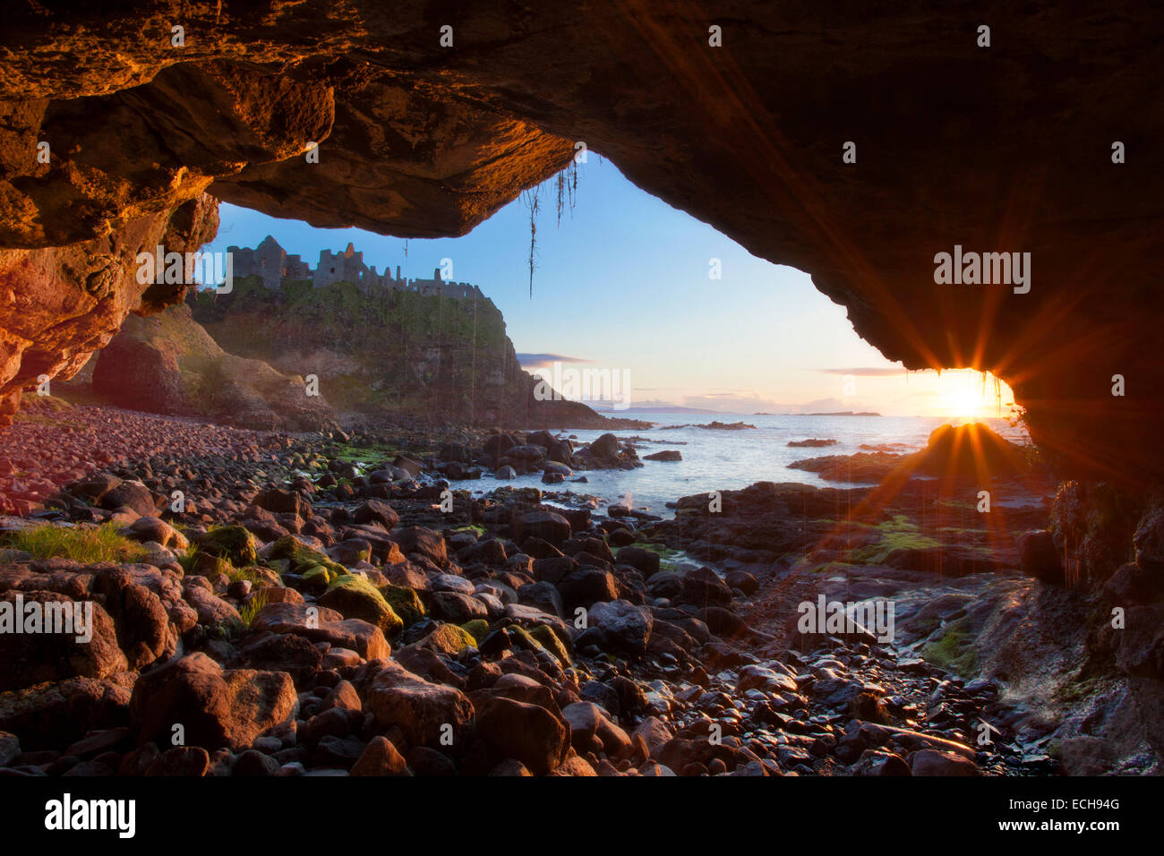 Höhle Sonnenuntergang Bilder Dunluce Castle, Causeway-Küste, County Antrim, Nordirland. Stockfoto