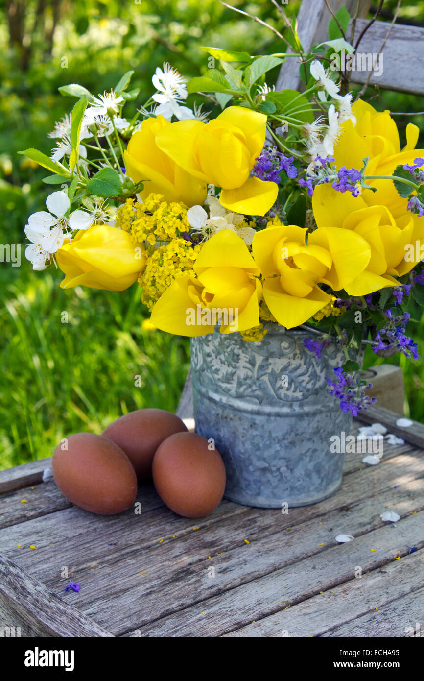 Strauß mit gelben Tulpen und Eiern auf Holzstuhl Stockfoto