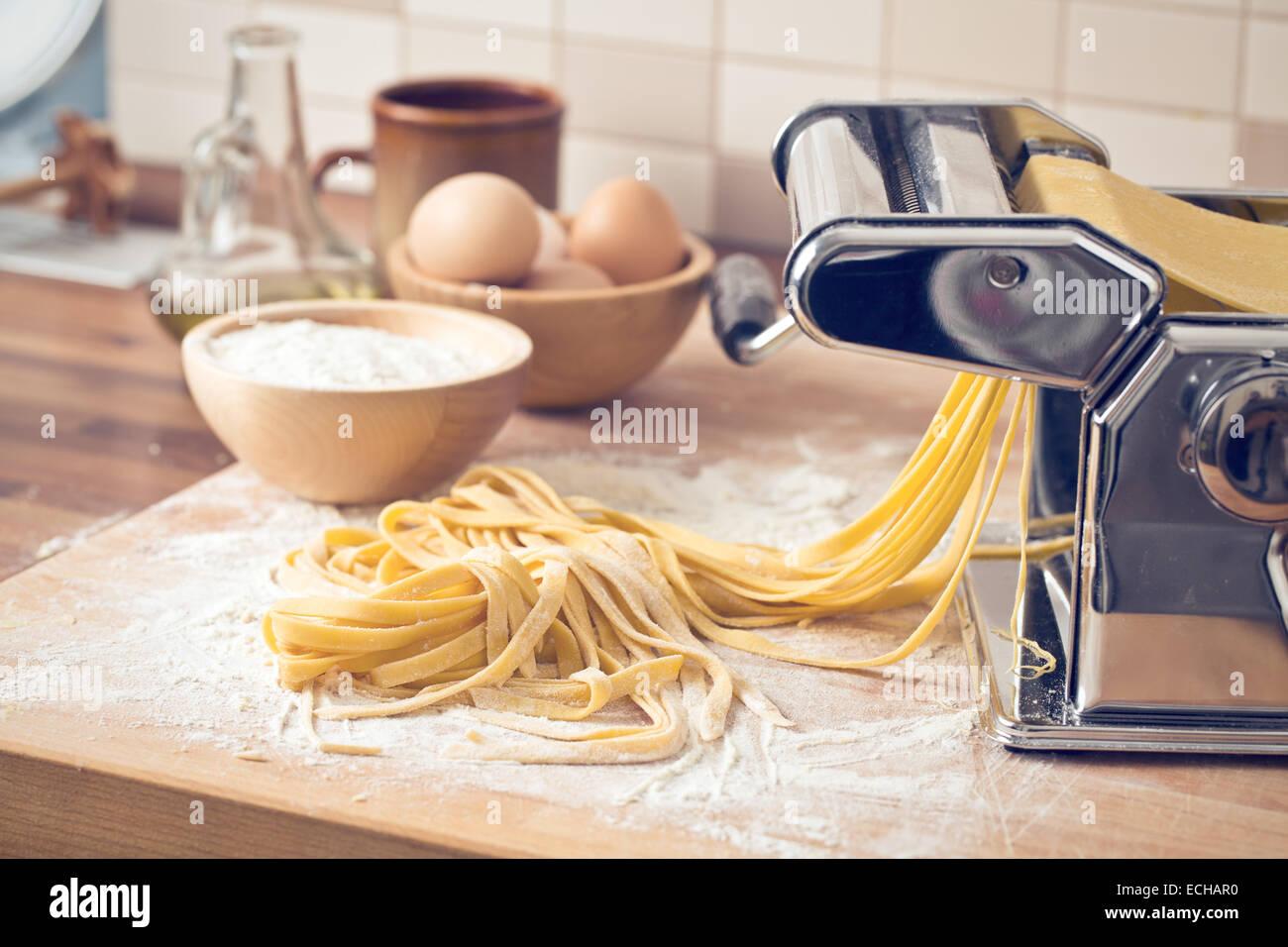 frische Nudeln und Pasta-Maschine am Küchentisch Stockfoto