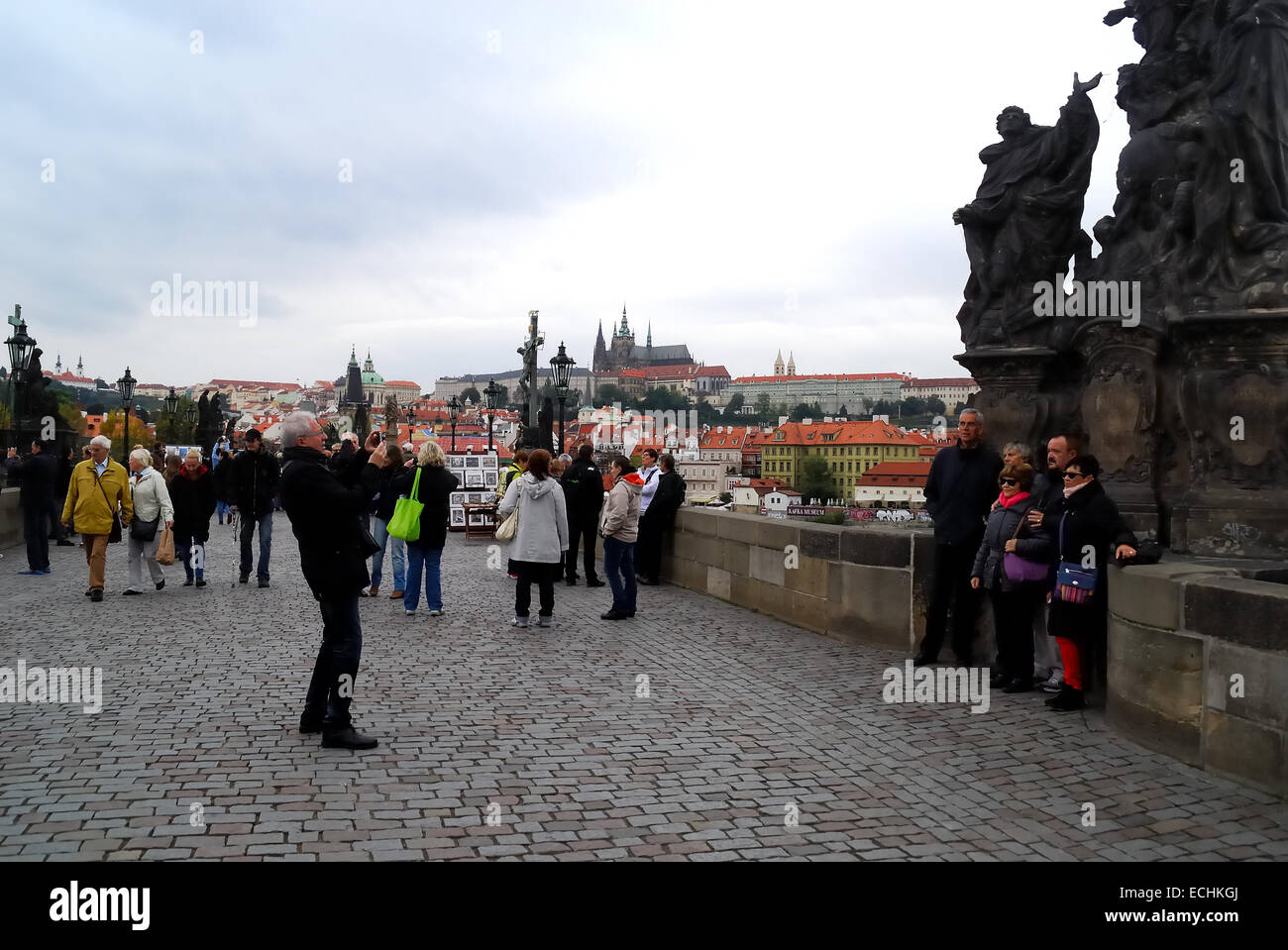 Tschechien, Prag. Touristen machen ein Erinnerungsfoto auf der Karlsbrücke, unter die Statuengruppe, die Madonna mit Heiligen Dominikus und Thomas von Aquin darstellt. Arbeit von Matěj Václav Jackl, 1708. Stockfoto