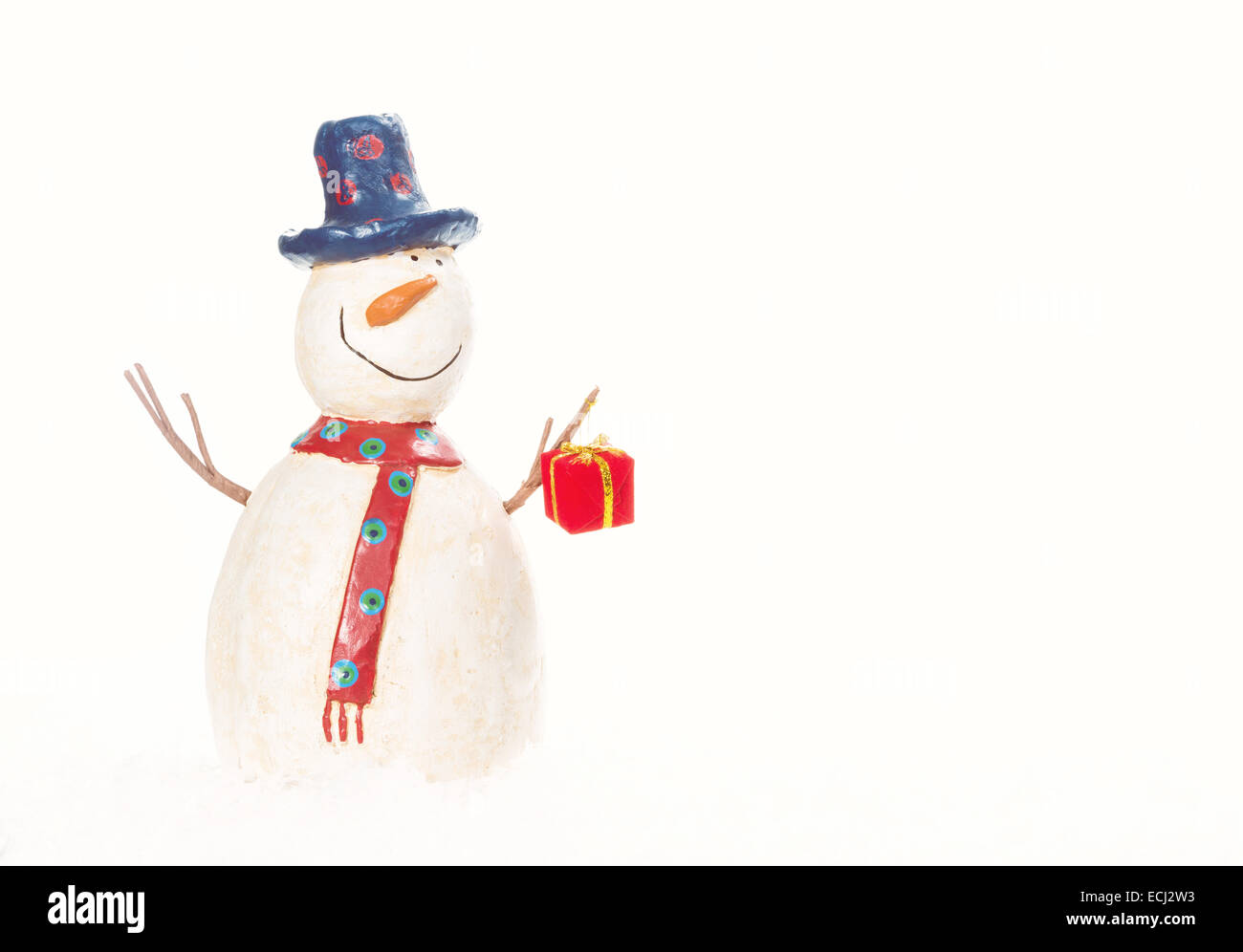 Dekorative Schneemann hält ein Weihnachtsgeschenk vor weißen Schnee Hintergrund Stockfoto