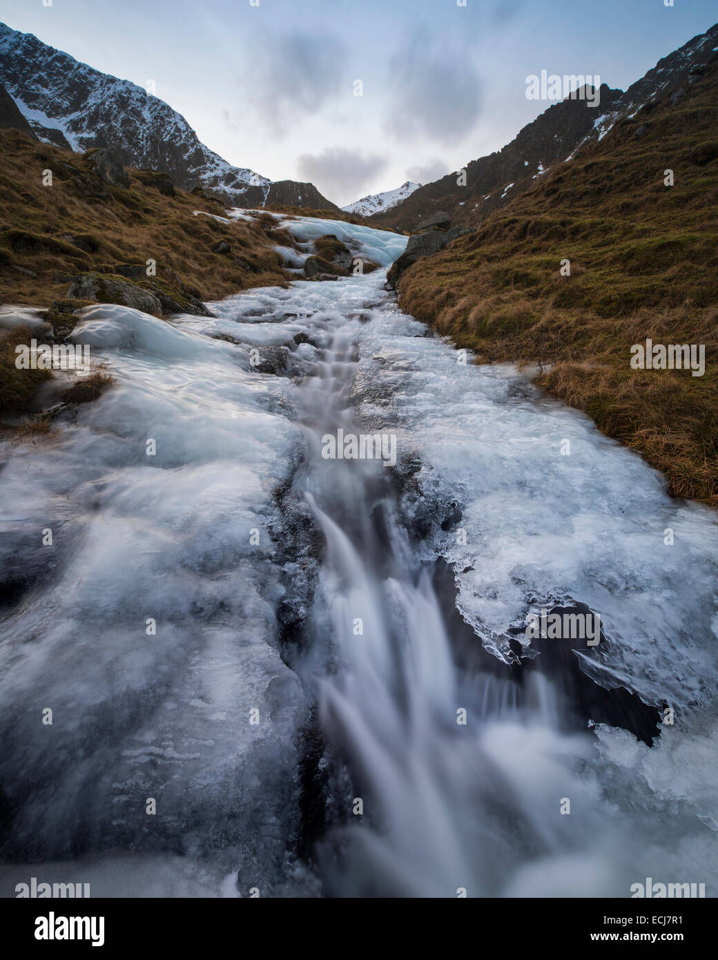 Wasser fließt durch einen schmelzenden Bergbach des Eises, Flakstadøy, Lofoten Inseln, Norwegen Stockfoto