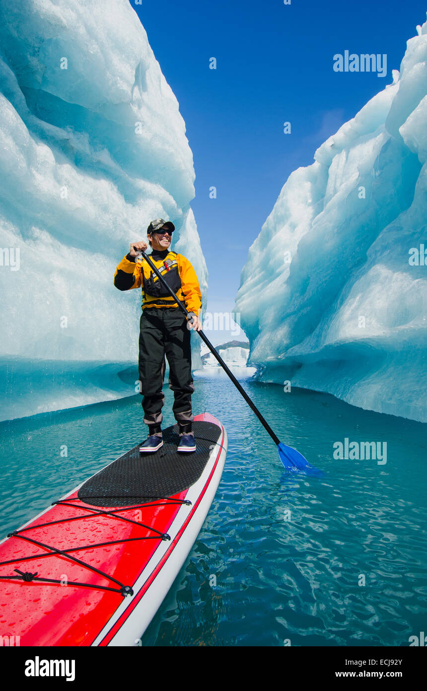Ein Mann auf Stand up Paddle Board (SUP) untersucht eine Eisberg Canyon auf Bear Lake in Kenai Fjords Nationalpark, Alaska. Stockfoto