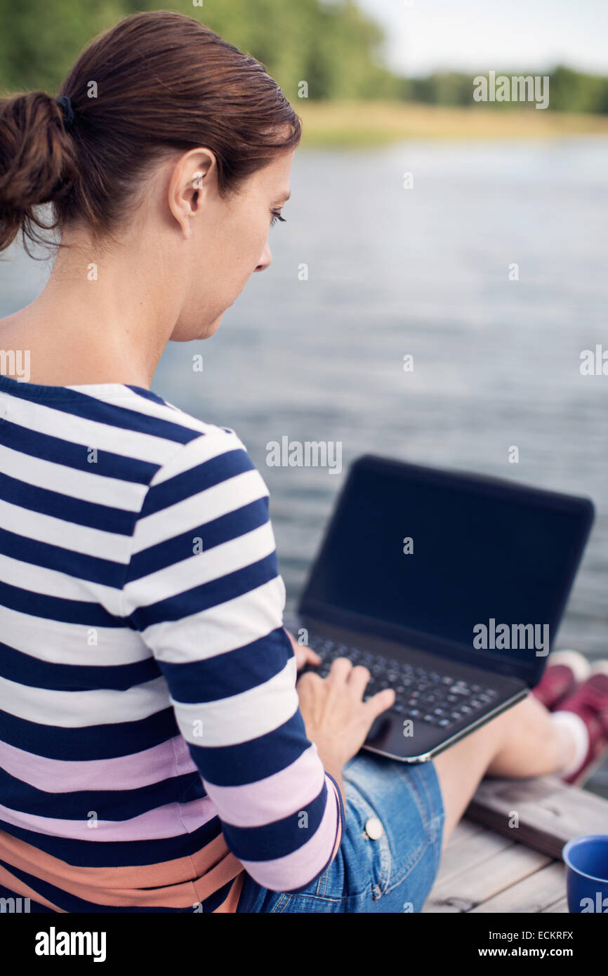 Voller Länge Seitenansicht des Reife Frau mit Laptop am pier Stockfoto