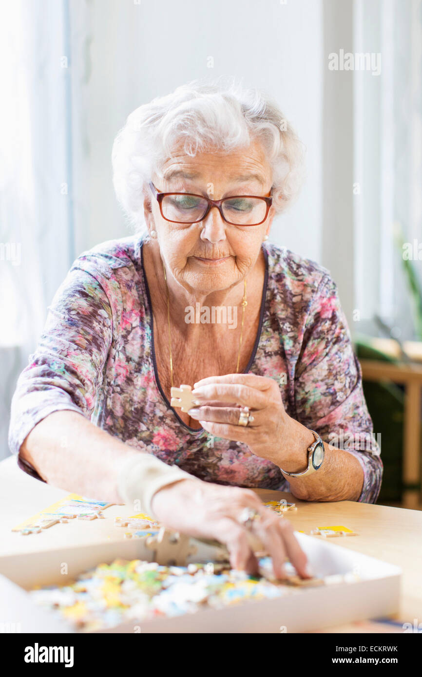 Ältere Frau Montage Puzzleteile an Tisch im Pflegeheim Stockfoto