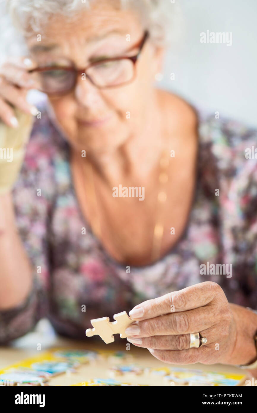 Ältere Frau Lösung Puzzle am Tisch im Pflegeheim Stockfoto