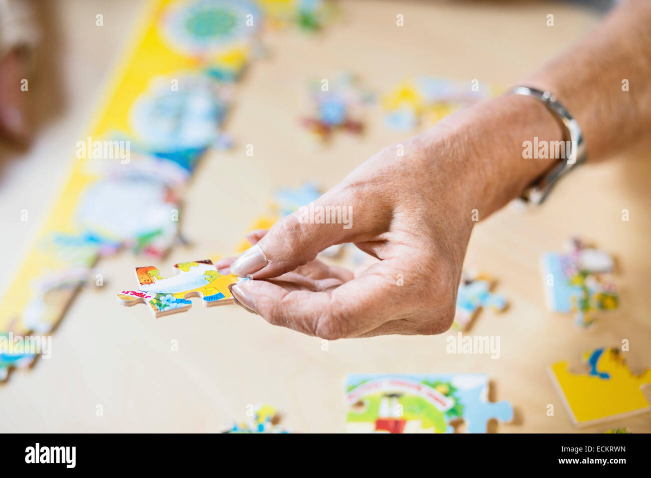 Zugeschnittenes Bild der senior Frau Hand hält Puzzleteil am Tisch im Pflegeheim Stockfoto