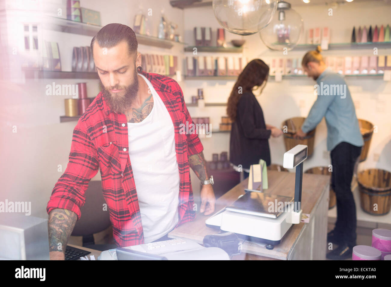 Eigentümer an Kasse beim Kunden einkaufen im Hintergrund stehend Stockfoto