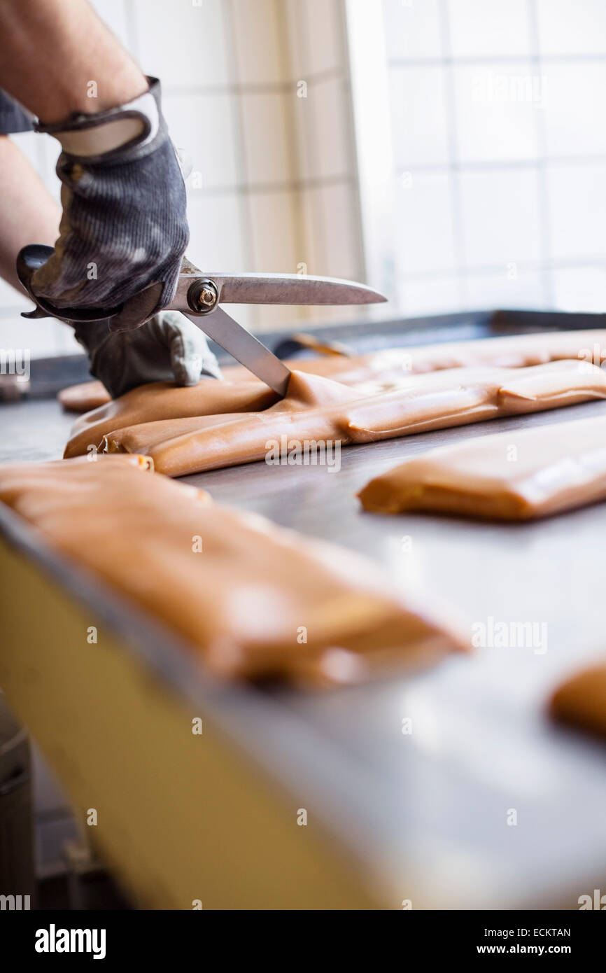 Bild von Arbeitskraft schneiden Karamell mit einer Schere im Süßwarenladen beschnitten Stockfoto