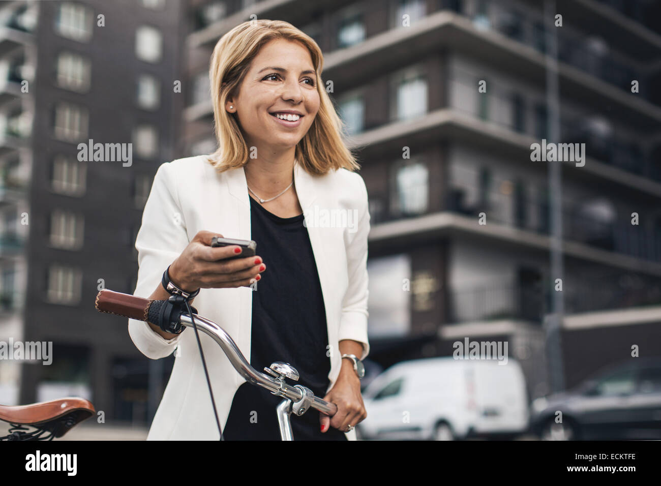 Lächelnde Geschäftsfrau mit Smartphone in Stadt Stockfoto