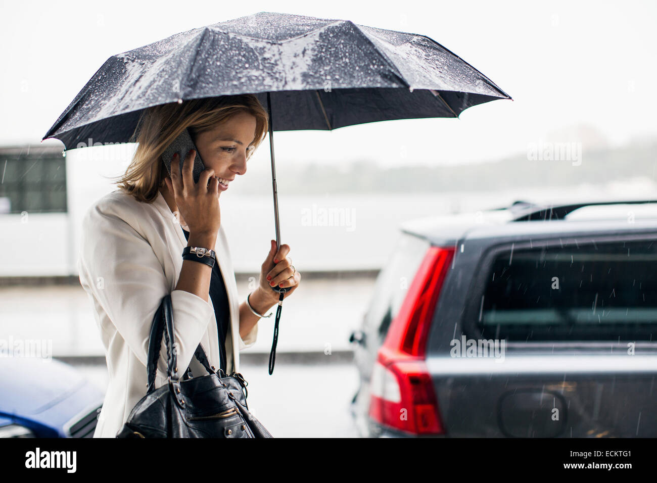 Geschäftsfrau sprechen auf Smartphone während der Regenzeit in Stadt Stockfoto