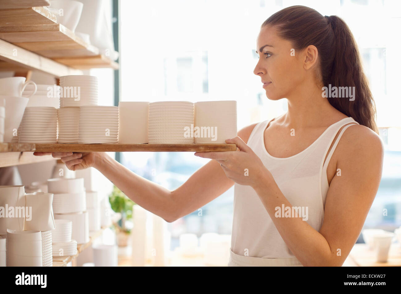 Junge Arbeitnehmerin, die Vermittlung von handwerklichen Produkten in Geschirr Werkstatt Stockfoto