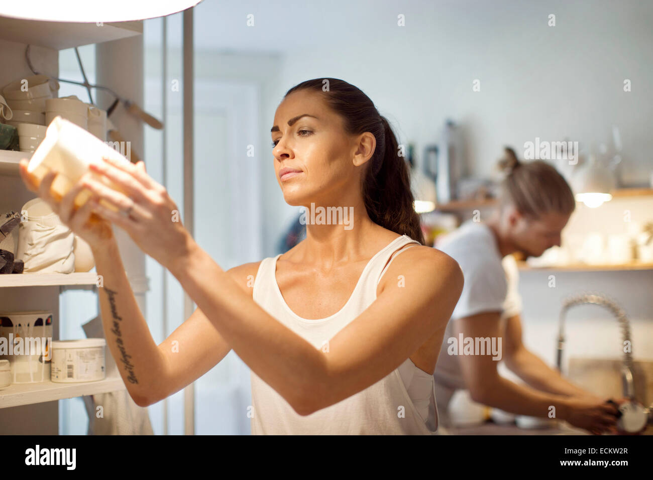 Arbeitnehmerin Blick auf Geschirr beim männlichen Kollegen arbeiten in Werkstatt Stockfoto