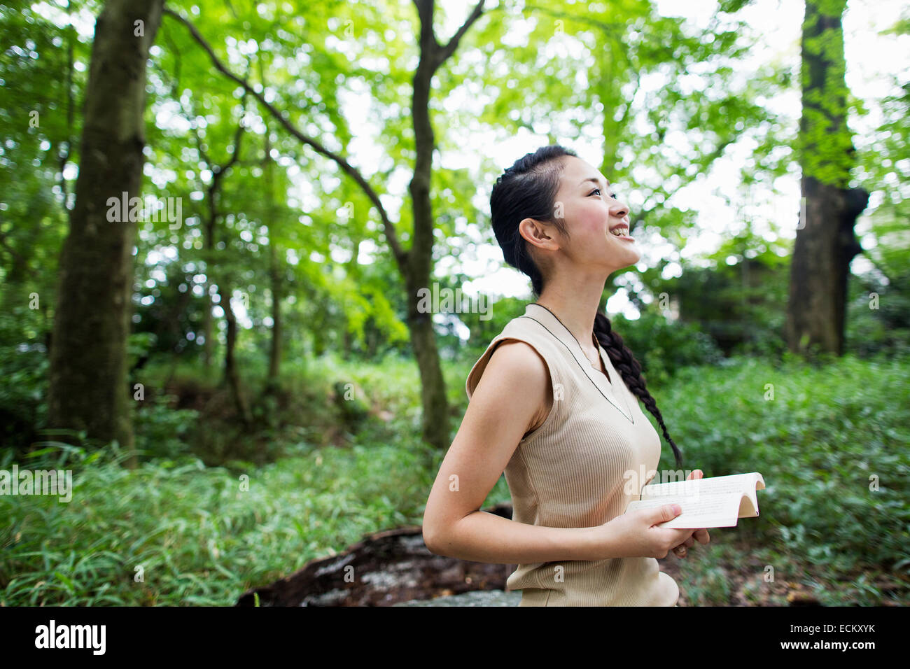 Junge Frau hält ein Buch in einem Wald. Stockfoto