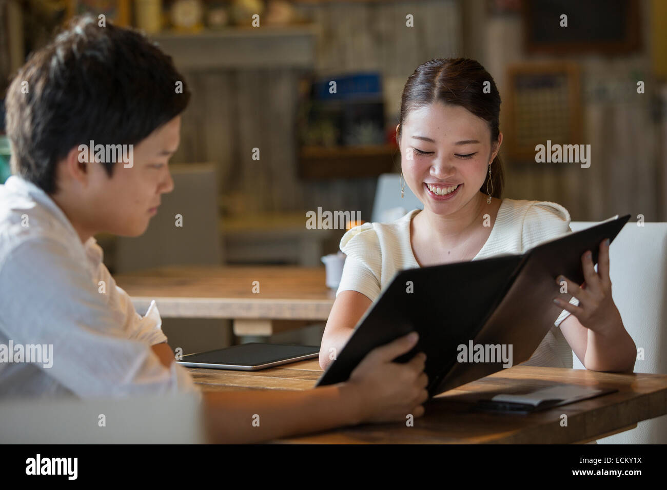 Frau und Mann sitzt an einem Tisch in einem Café, Blick auf die Speisekarte, lächelnd. Stockfoto