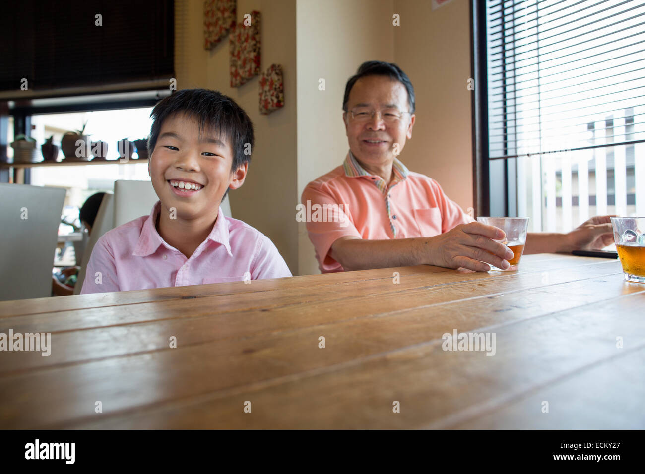 Mann und junge sitzen an ein Esszimmer Tisch, lächelnd. Stockfoto