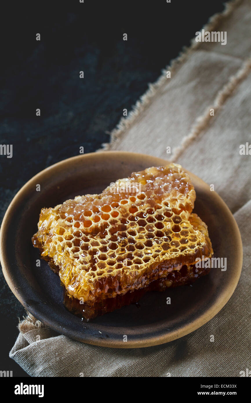 Bienenwabe auf Keramikplatte über alten Holztisch. Stockfoto