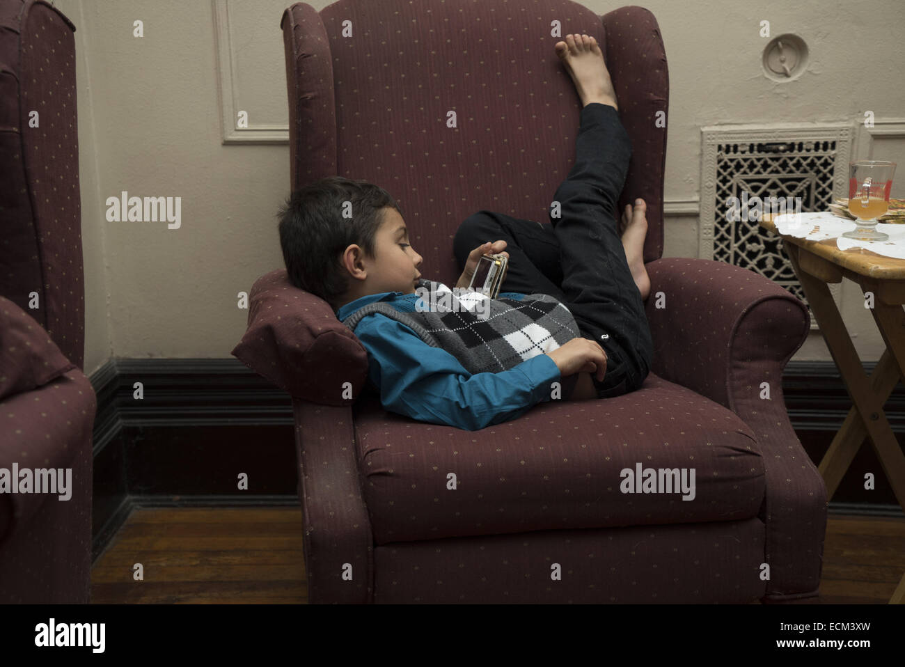 Fünf Jahre alten Jungen Uhren einen Film auf seine Mutter Iphone zu Hause. Stockfoto