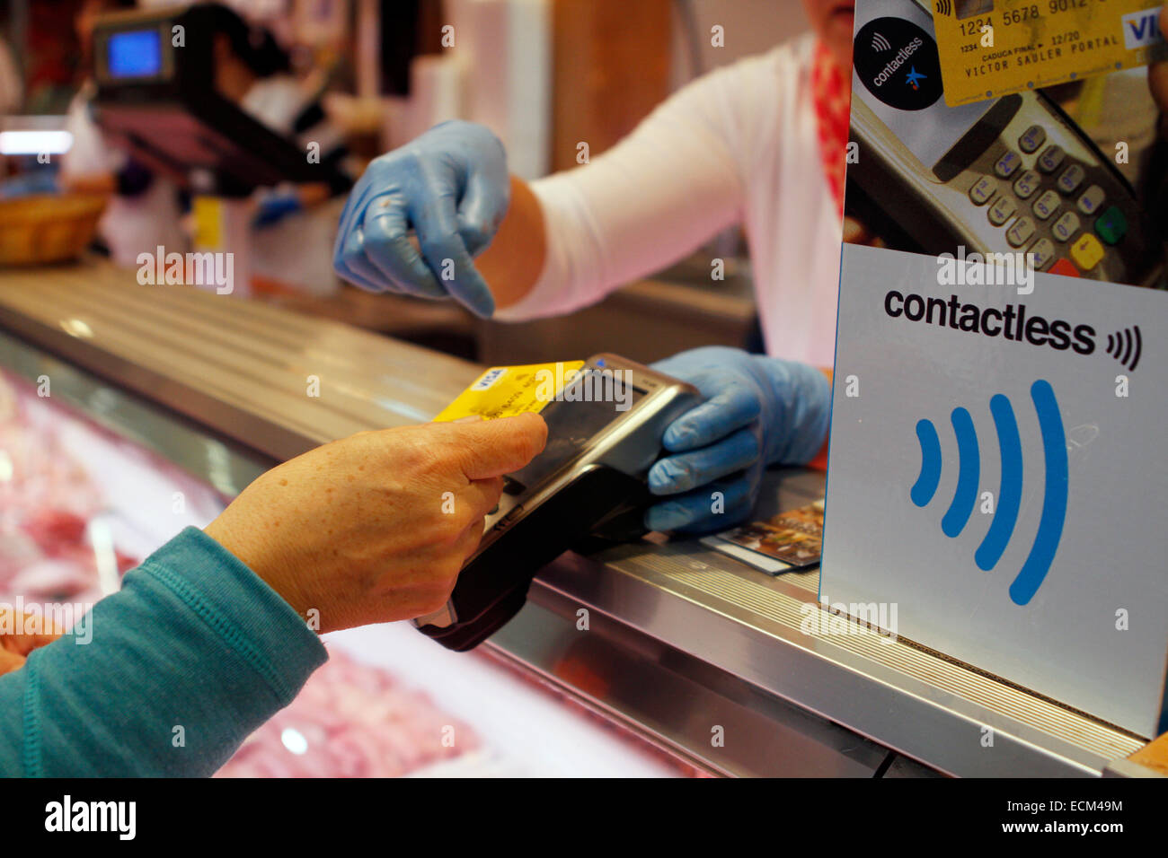 Eine Frau zahlt für eine Metzgerei mit einem kontaktlosen Kreditkarten-System in Mallorca, Spanien Stockfoto
