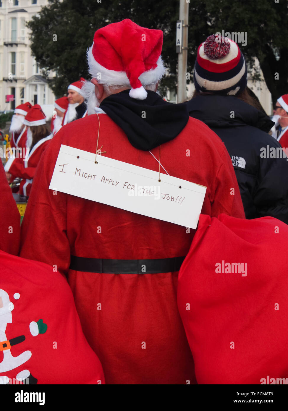 Eine Teilnahme an der Portsmouth Santa Run Santa trägt ein Schild mit der Aufschrift "Ich könnte für den Job bewerben" Stockfoto