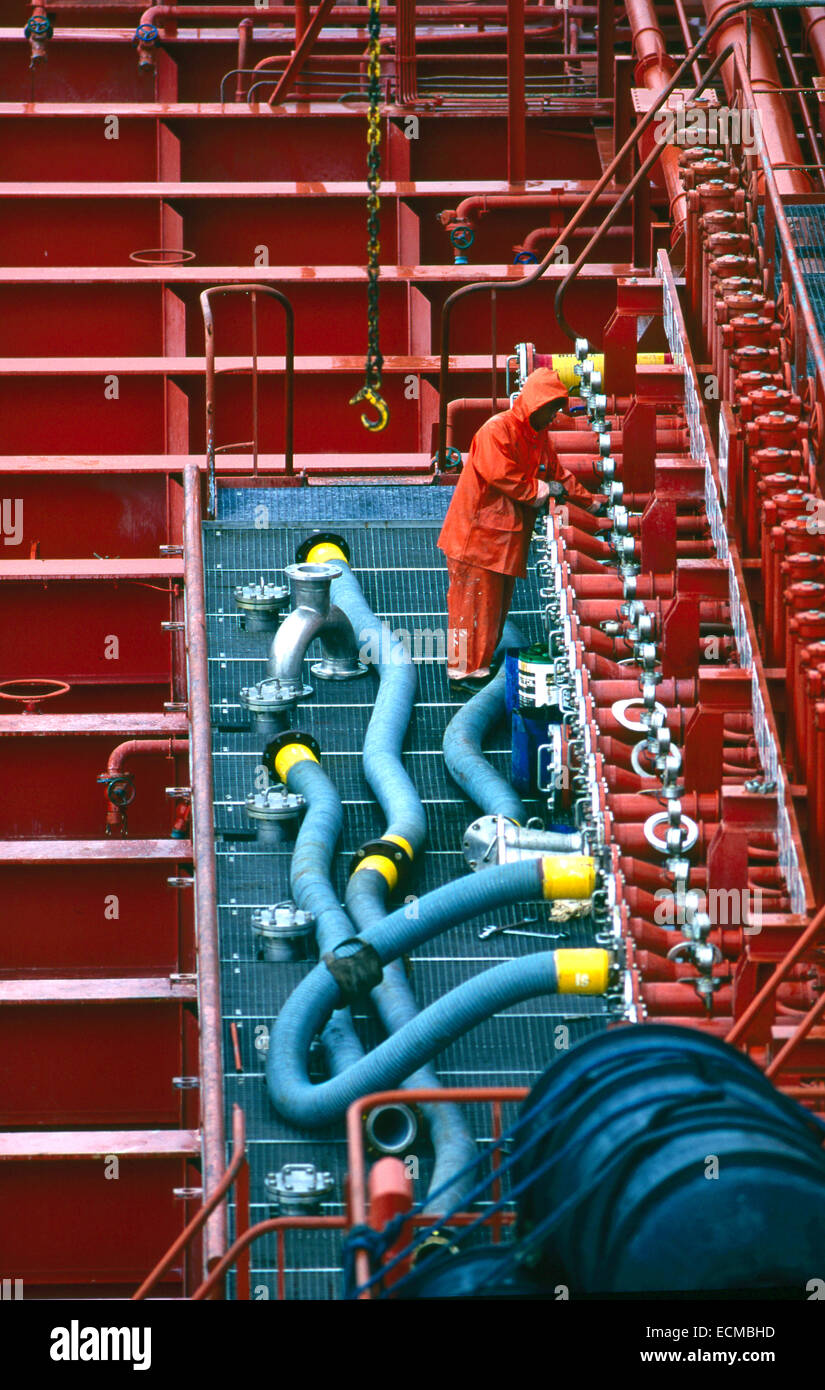 Arbeiter sicher hält, Luken und Ausrüstung auf dem orange Deck eines Öltankers wie es bereitet sich auf den Hafen verlassen. Stockfoto