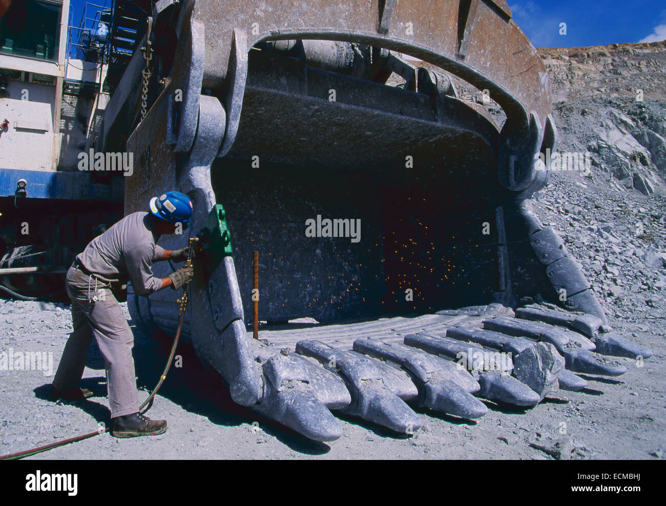 Ein Schweißgerät Reparatur einen riesigen Schaufel Eimer in einem Tagebau. Stockfoto