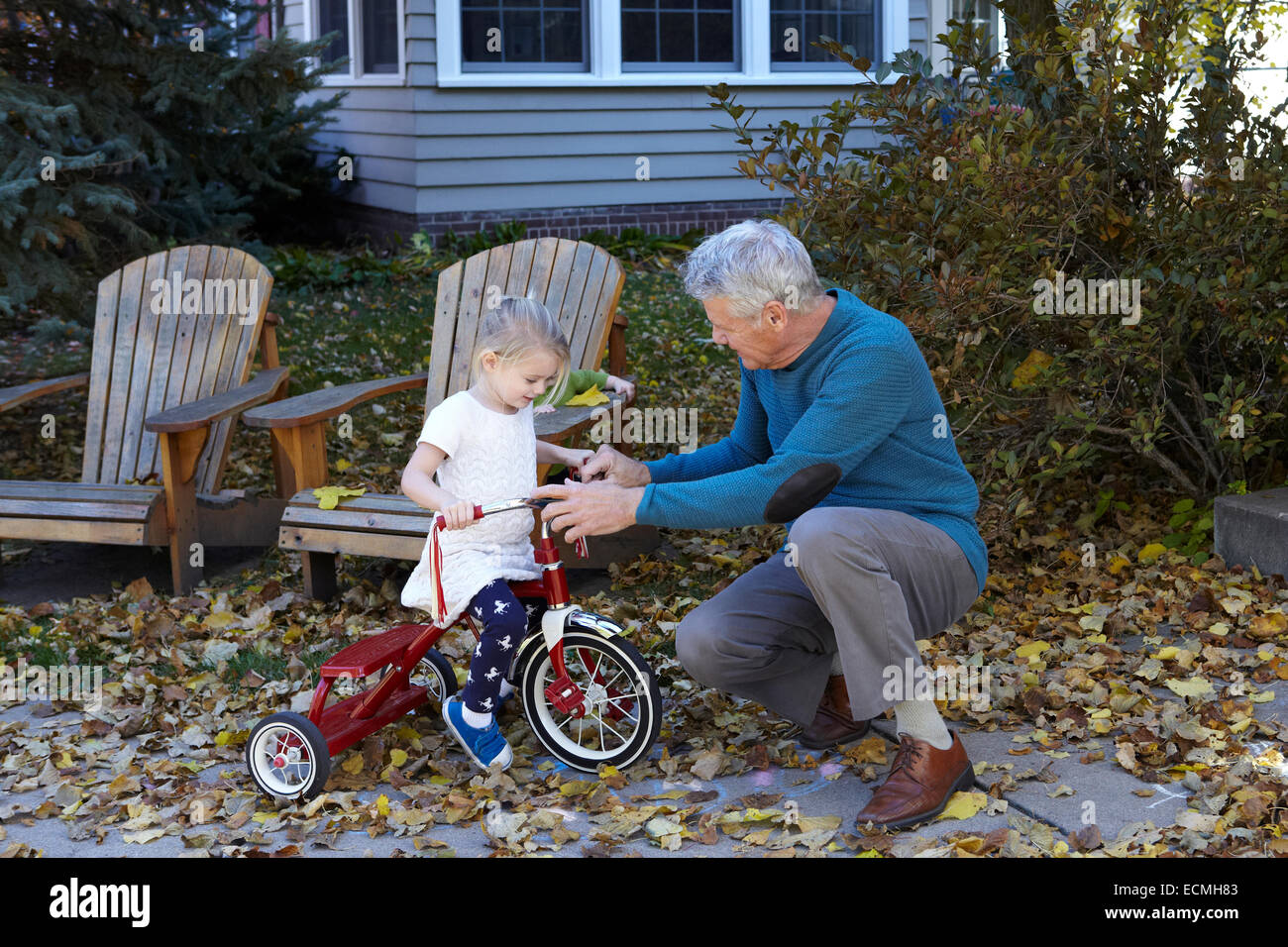 Großvater lehrt seine Enkelin ein Dreirad fahren Stockfoto