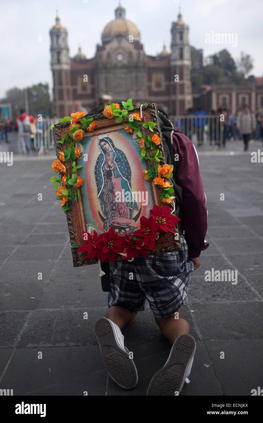 Ein Mann zu Fuß auf den Knien tragen ein Bild der Jungfrau von Guadalupe mit Blumen geschmückt. Wallfahrt zur Basilika o Stockfoto
