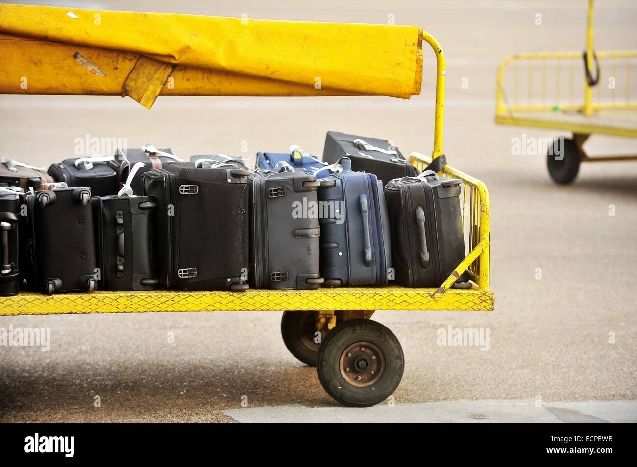 Gelben Wagen beladen mit Gepäck auf einer asphaltierten Strecke Flughafen Stockfoto
