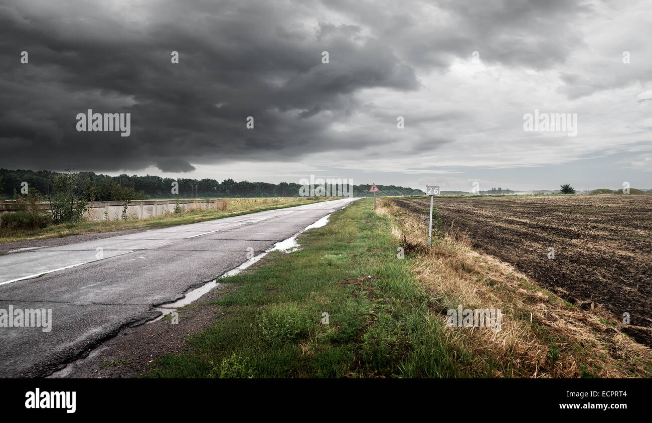 Straße bei bewölktem Wetter gegen Gewitterwolken Stockfoto