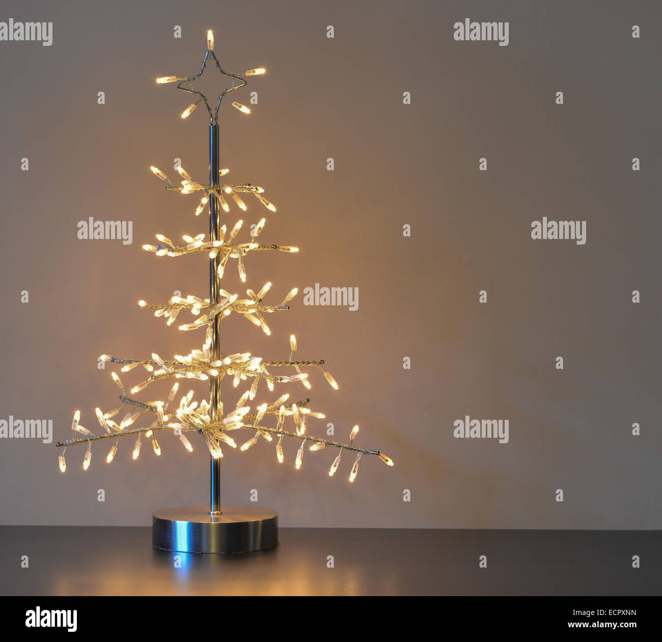 Silber Metall Weihnachtsbaum Dekoration auf Tisch mit warmes weißes Licht stehend Stockfoto