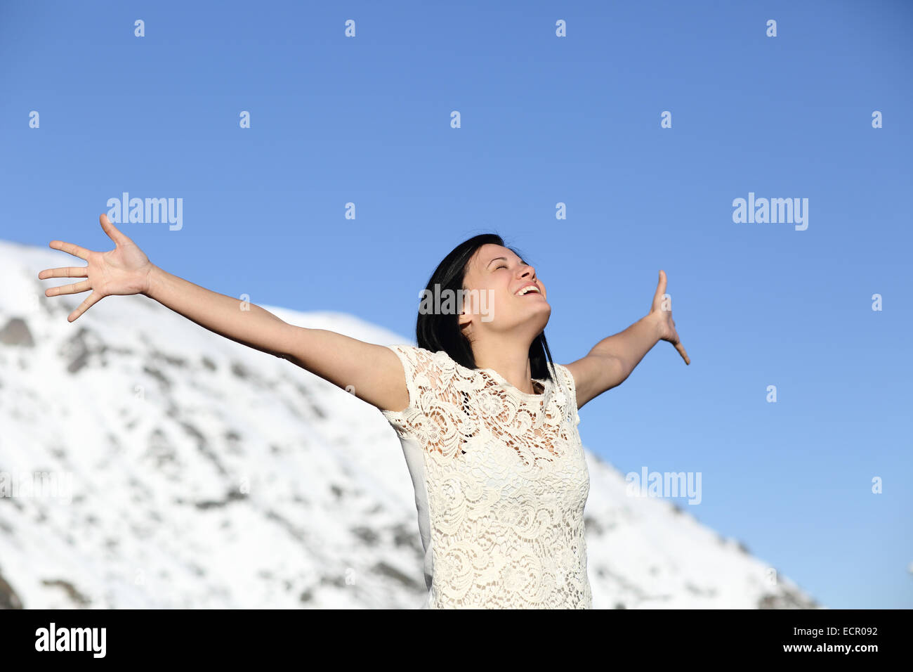 Froh, dass Frau atmet tief Anhebung im Winter mit Himmel und einen schneebedeckten Berg im Hintergrund Arme Stockfoto