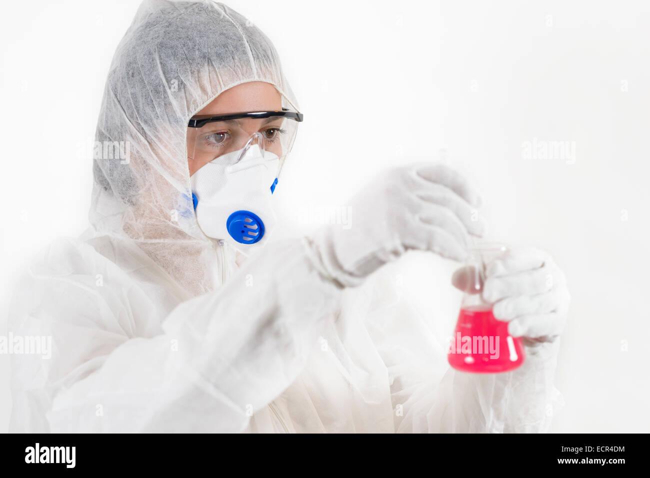 Junge Frau trägt Schutzanzug hält einige Laborglas isoliert auf weiss Stockfoto