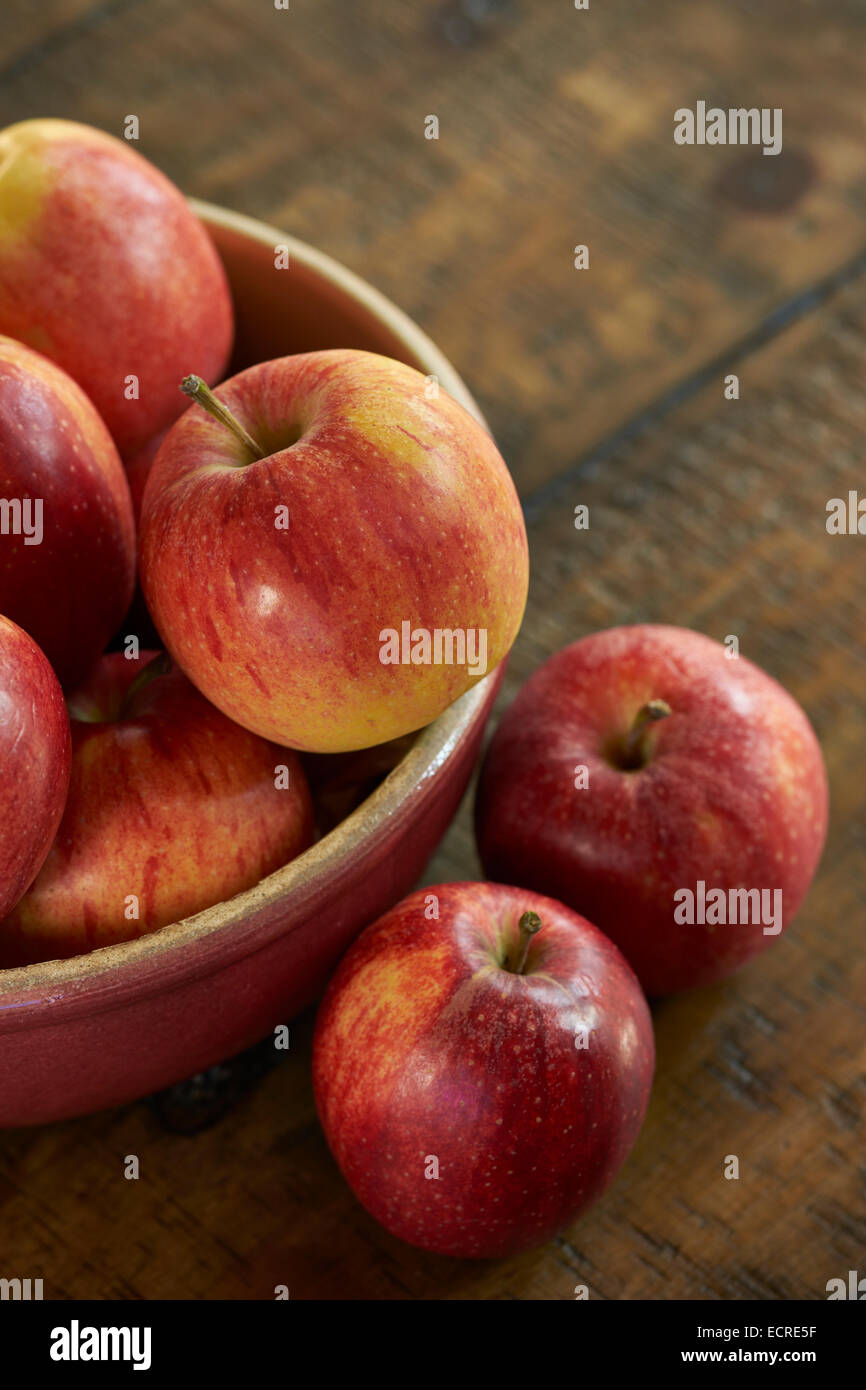 Frische rote Äpfel in einen Darm auf einem rustikalen Holztisch. Stockfoto