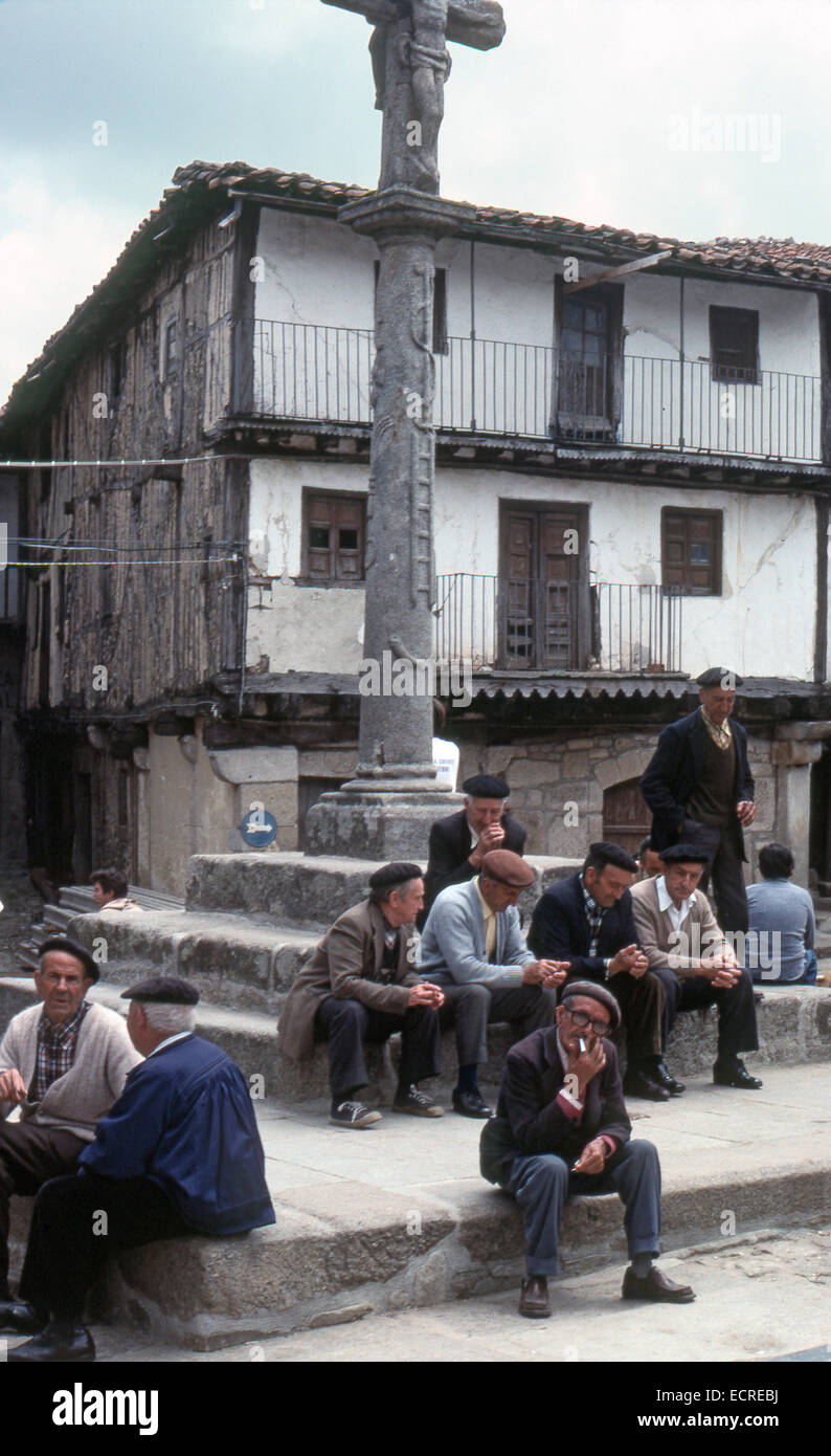 Eine Gruppe Alter Männer sitzen auf den Stufen des "Rollo" befindet sich auf dem Hauptplatz von einem mittelalterlichen Dorf mit der "Sierra de Franci Stockfoto