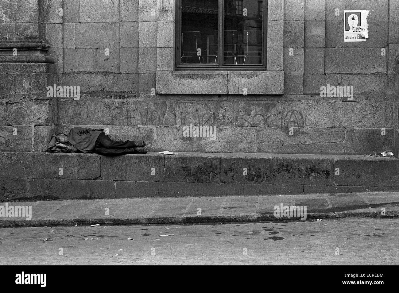 Ein arbeitsloser Mann schläft auf der Straße unter einer gemalten "soziale Revolution" während der "spanischen demokratischen Übergang" am August Stockfoto