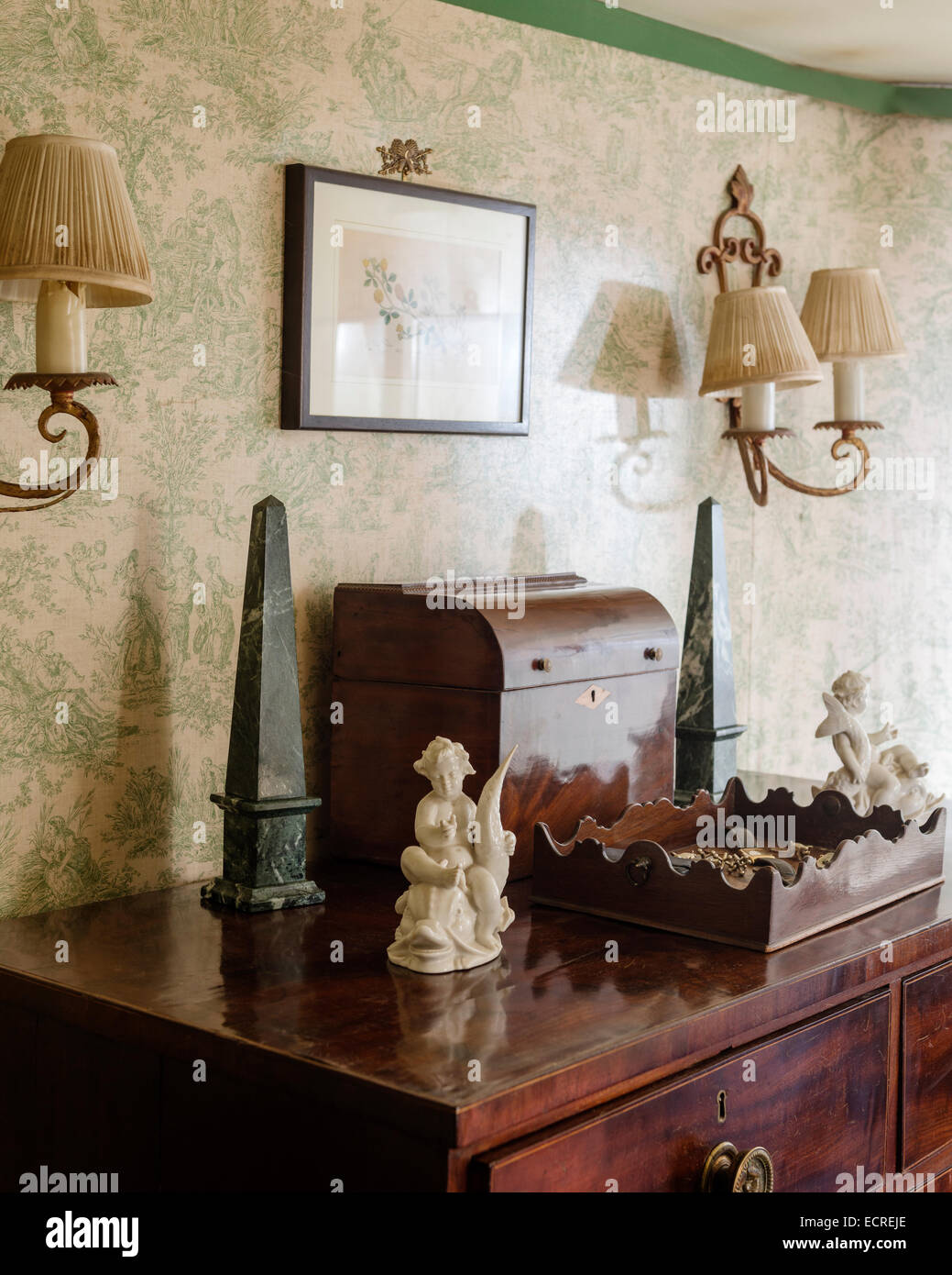 Ornamente auf antiken Holzkiste in Raum mit Toile De Jouy Tapete und Wand Wandleuchter Stockfoto