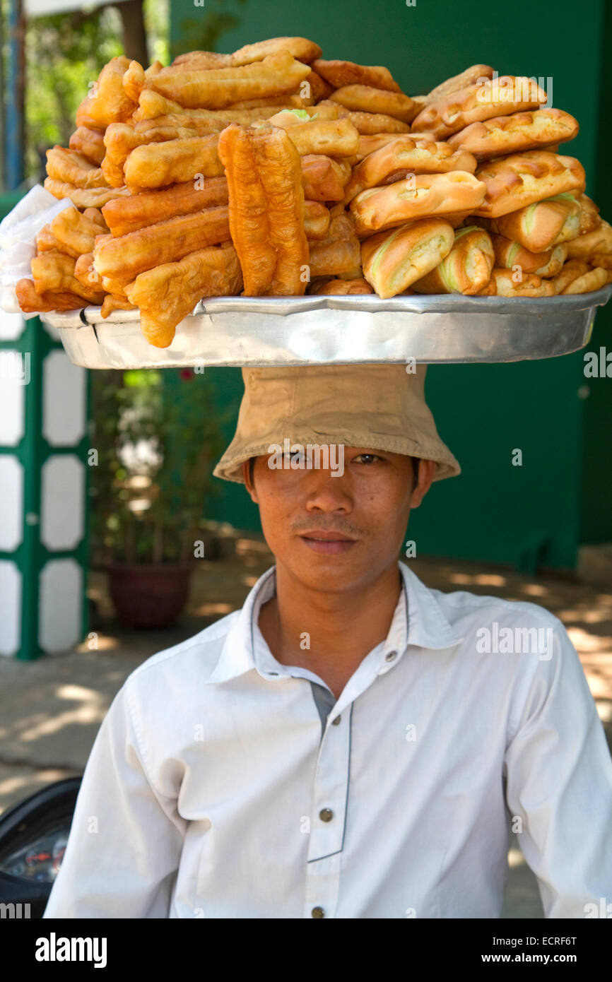 Vietnamesische Anbieter gleicht gebackene süße Snacks auf dem Kopf in Nha Trang, Vietnam. Stockfoto
