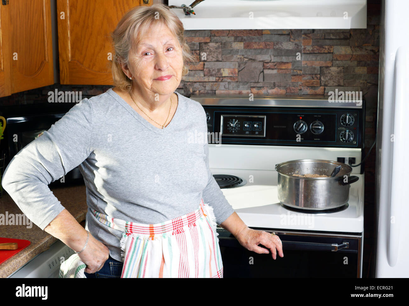Freundlich lächelnden Großmutter oder Senior Frau Kochen in ihrer Küche Stockfoto