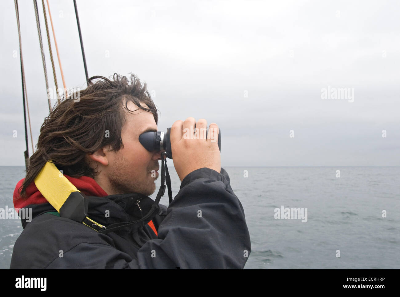 Junge Segler auf der Suche im Fernglas von Bord eines Schiffes Stockfoto