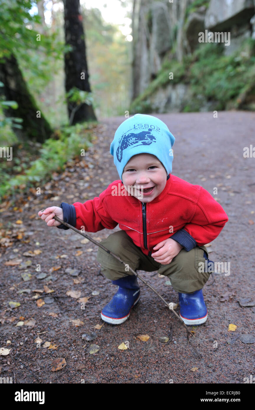 Kleiner Junge hält einen Stock lächelnd Stockfoto