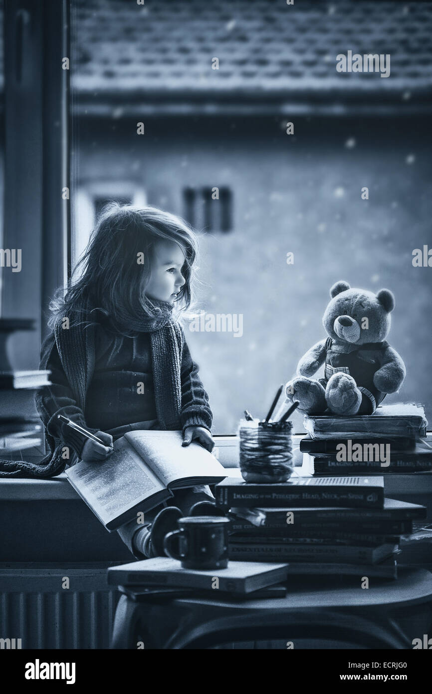 Entzückende kleine Mädchen, Brief an den Weihnachtsmann, sitzt auf einem Fenster, Bücher und Teddybär rund um Stockfoto