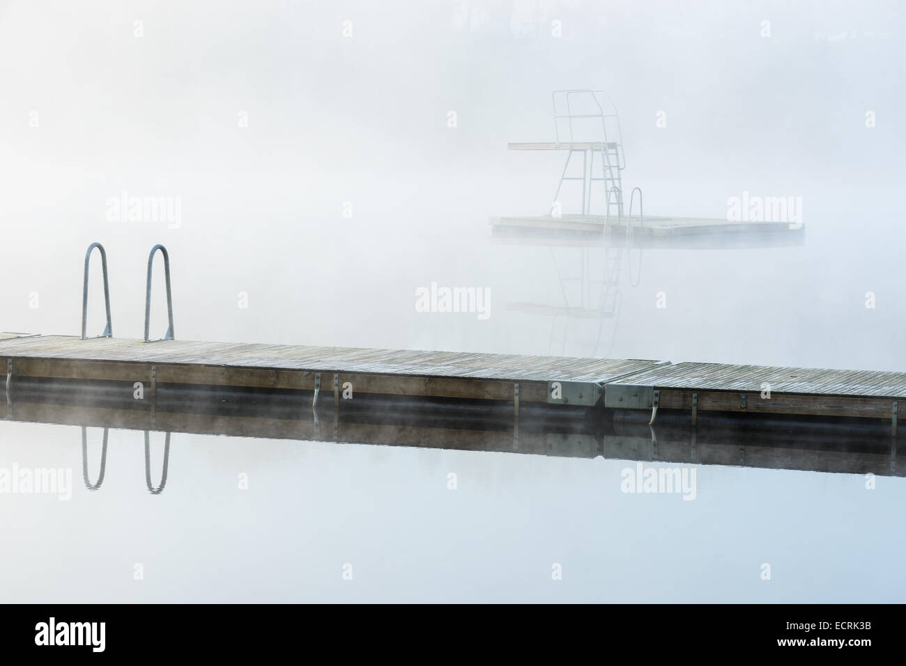Hölzerne Dock und ein Sprungbrett in einem nebligen See Stockfoto